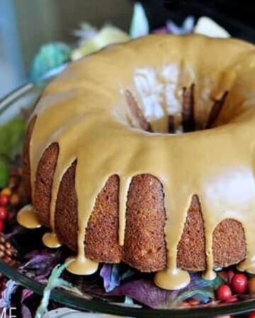 Pumpkin Bundt Cake with Biscoff glaze, on a platter decorated with fall leaves and berries.