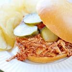 Slow Cooker Chicken Sloppy Joes with pickles on a plate with potato chips.