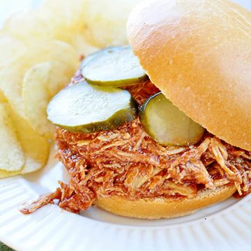 Slow Cooker Chicken Sloppy Joes with pickles on a plate with potato chips.