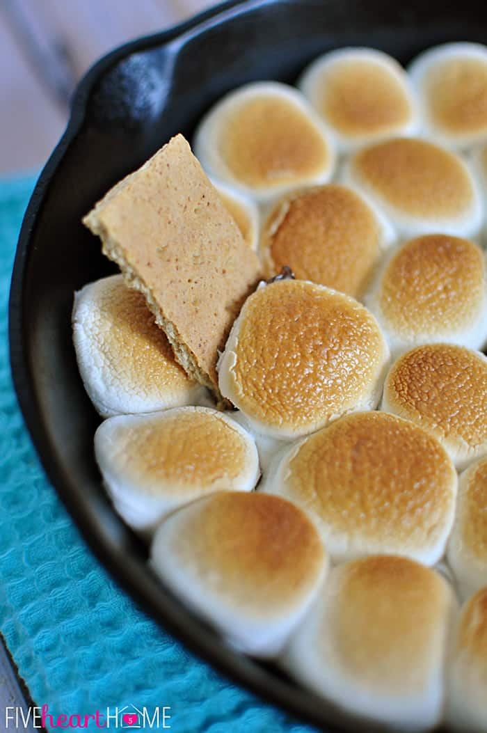 S'mores Dip ~ melted chocolate and toasty marshmallows bake up in a skillet; scoop up with graham crackers for a perfect party dessert! | FiveHeartHome.com S'mores Dip recipe in skillet with graham cracker dipper.