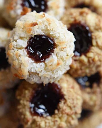 Close-up of Jam Thumbprint Cookies coated with nuts and coconut.