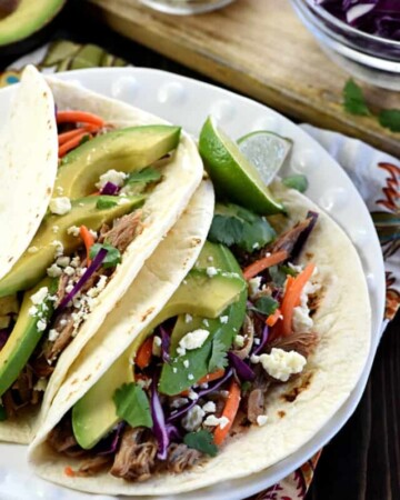 Slow Cooker Honey Lime Pulled Pork Tacos ~ tender, spicy-sweet pork piled on flour tortillas and topped with red cabbage, carrots, avocado, cotija cheese, and fresh cilantro for an easy, effortless dinner...and the leftover pork is fantastic on nachos! | FiveHeartHome.com