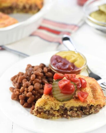 Impossible Cheeseburger Pie without Bisquick on plate with dish in background.