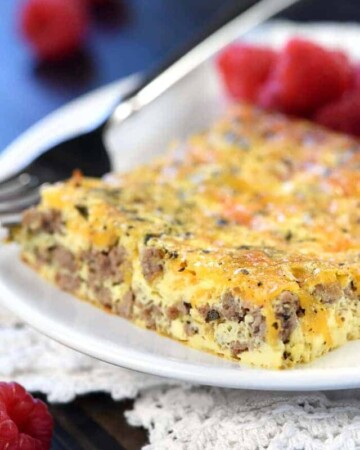 Slice of beef and cheese breakfast casserole on a plate with raspberries