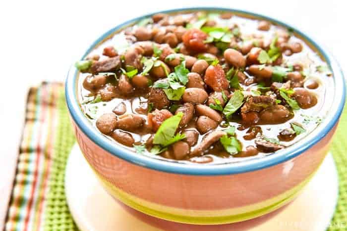 Slow Cooker Charro Beans ~ flavored with bacon, garlic, tomatoes, green chiles, jalapeños, cilantro, and spices, this crock pot recipe is the perfect side dish for Mexican food! | FiveHeartHome.com