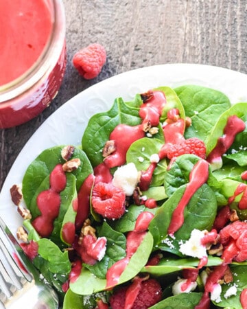 Aerial view of Raspberry Vinaigrette in jar and drizzled over salad.
