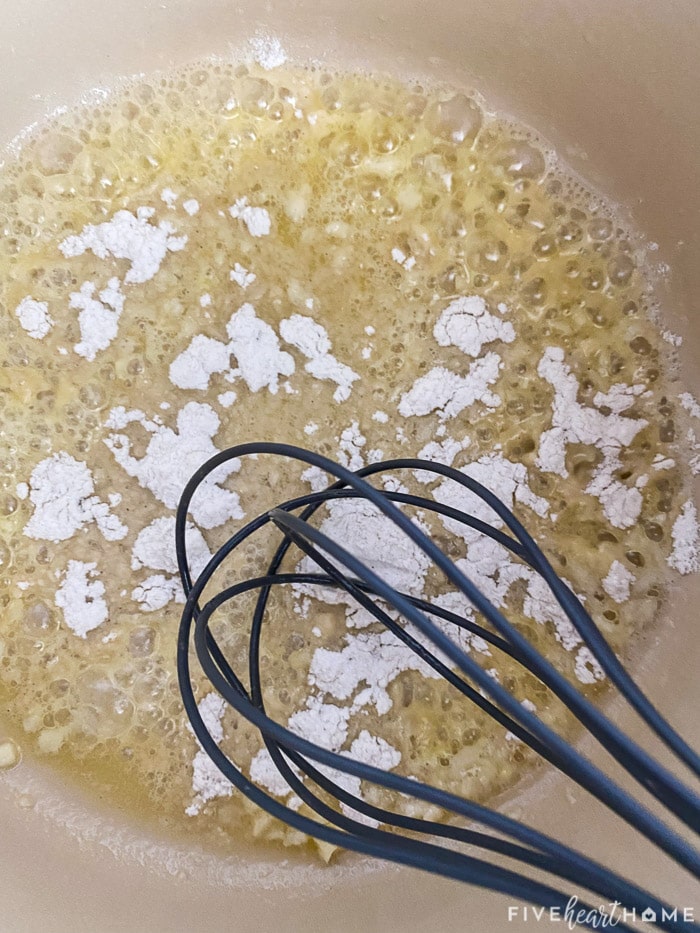 Flour sprinkled over butter in pot.