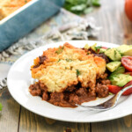 Tamale Pie recipe served on a plate with avocado tomato salad on the side.