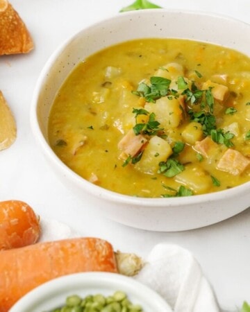 Slow Cooker Split Pea Soup in bowls with dried peas and carrots on side.