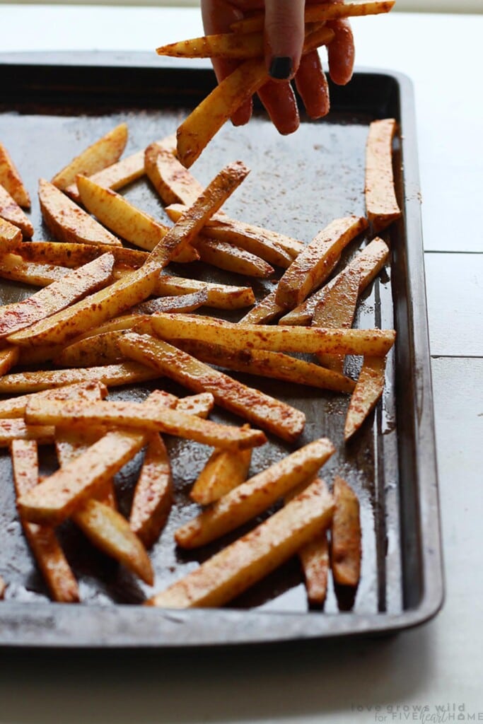 French fries seasoned on pan and ready for oven.
