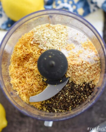 Aerial view of Lemon Pepper Seasoning ingredients in food processor; how to make lemon pepper seasoning with lemon zest and black peppercorns.