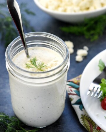 Jar of Feta Dressing with spoon sticking out.
