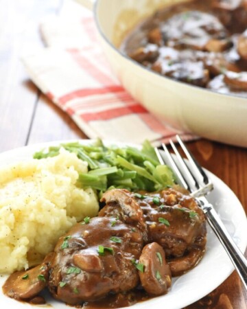 Hamburger Steak and gravy in skillet and on plate.
