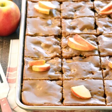 Caramel Apple Cake sliced in pan with caramel glaze and apple garnish.