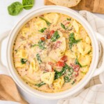 Sausage Tortellini Soup in white pot with wooden spoon.