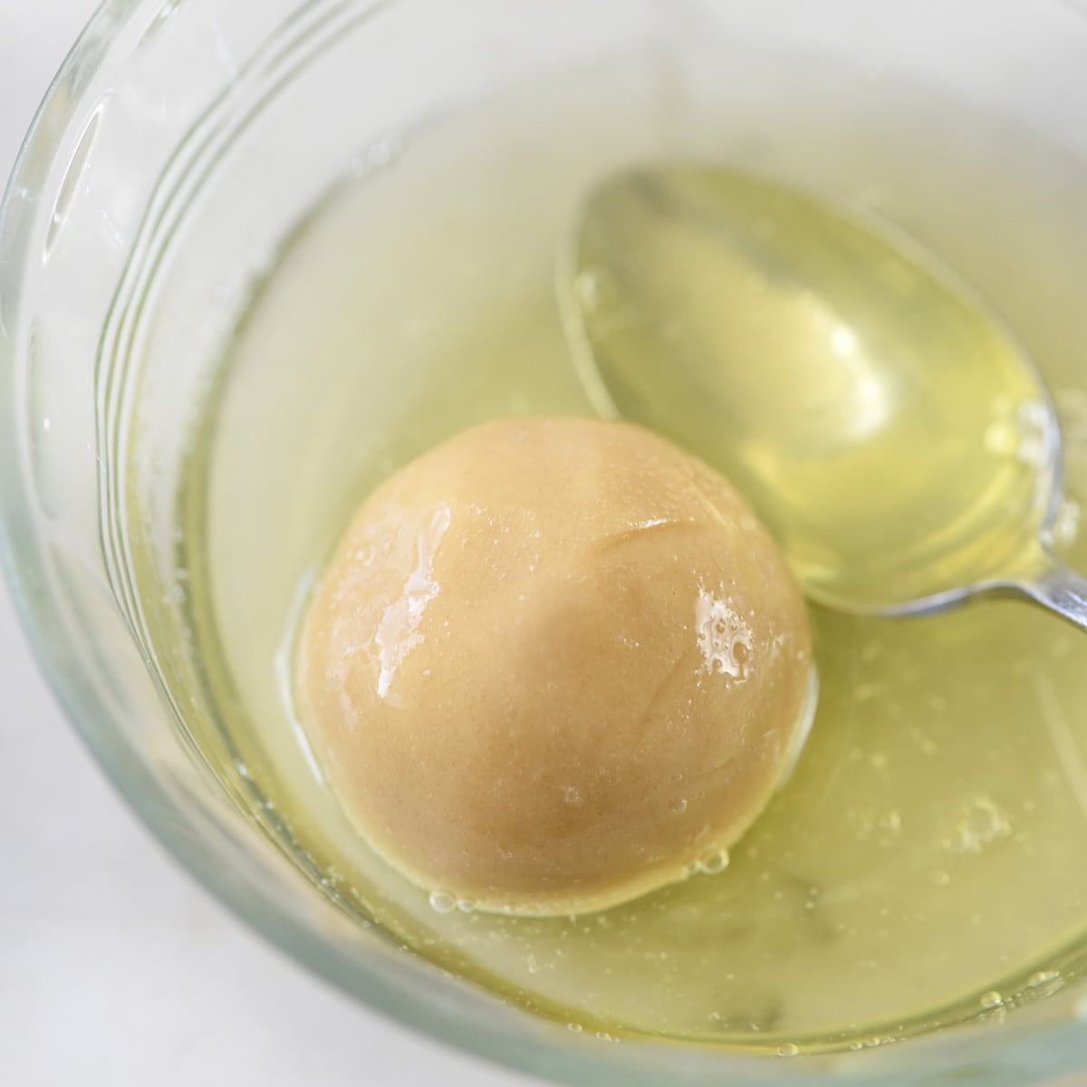 Rolling thumbprint cookie in egg white.